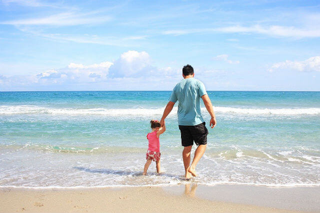 海辺を歩く父と娘